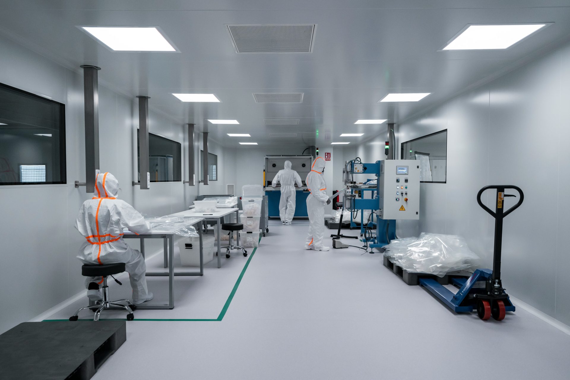 Workers in protective suits inside a sterile laboratory.